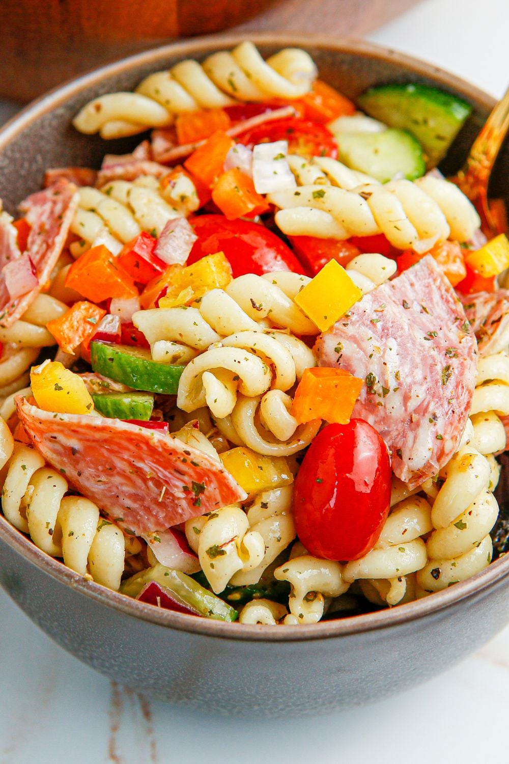 Summer Pasta Salad in a bowl on table with close up of vegetables 