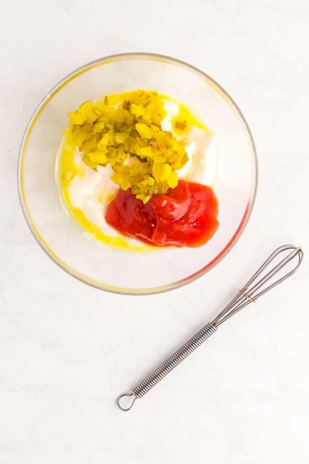 ingredients for the Big Mac Salad sauce in a glass bowl with whisk by it