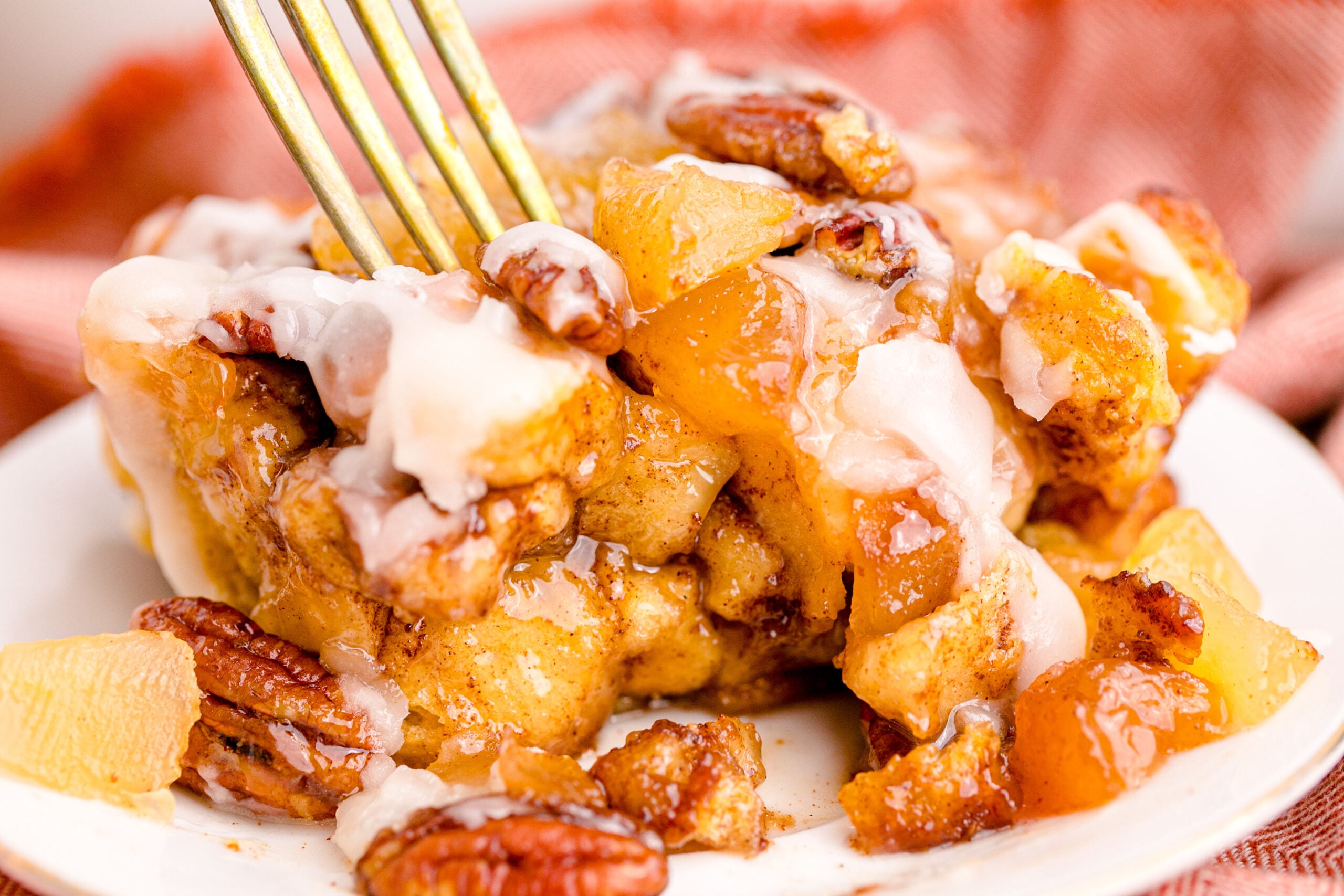 Cinnamon Roll Casserole on a white plate with a gold fork removing a bite.
