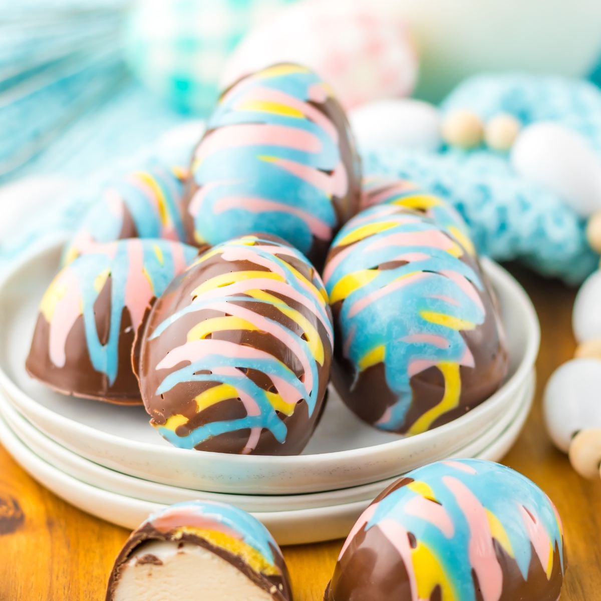 Easter Marshmallow Eggs on a plate on table wih an egg slice in half to show the marshmallow filling sitting on table 