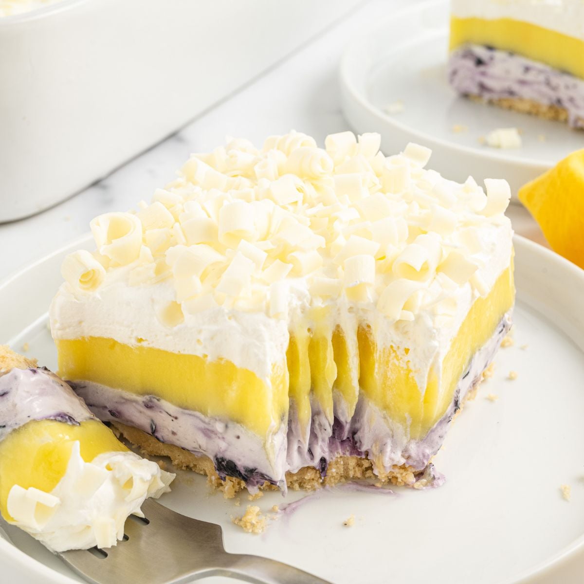Lemon Blueberry Lush sliced on plate with a fork with a bite on it