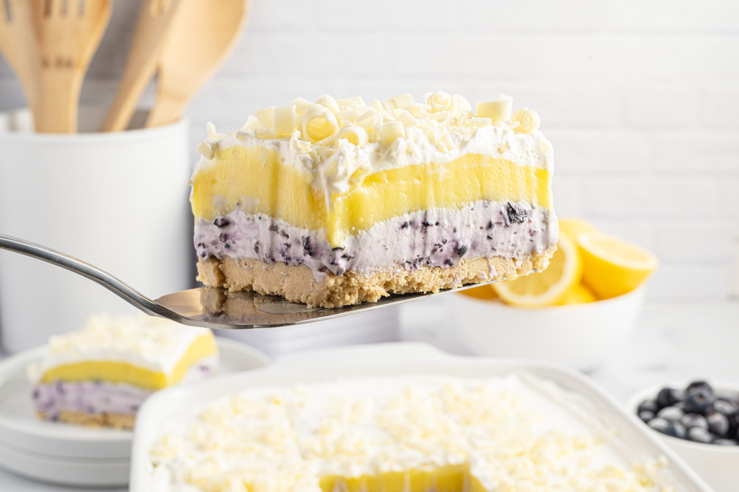 piece of lemon blueberry lush being lifted out of a white baking pan
