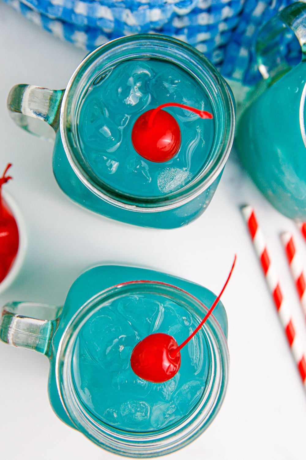 Blue Hawaiian Punch in mason jar glasses on table with straws around it