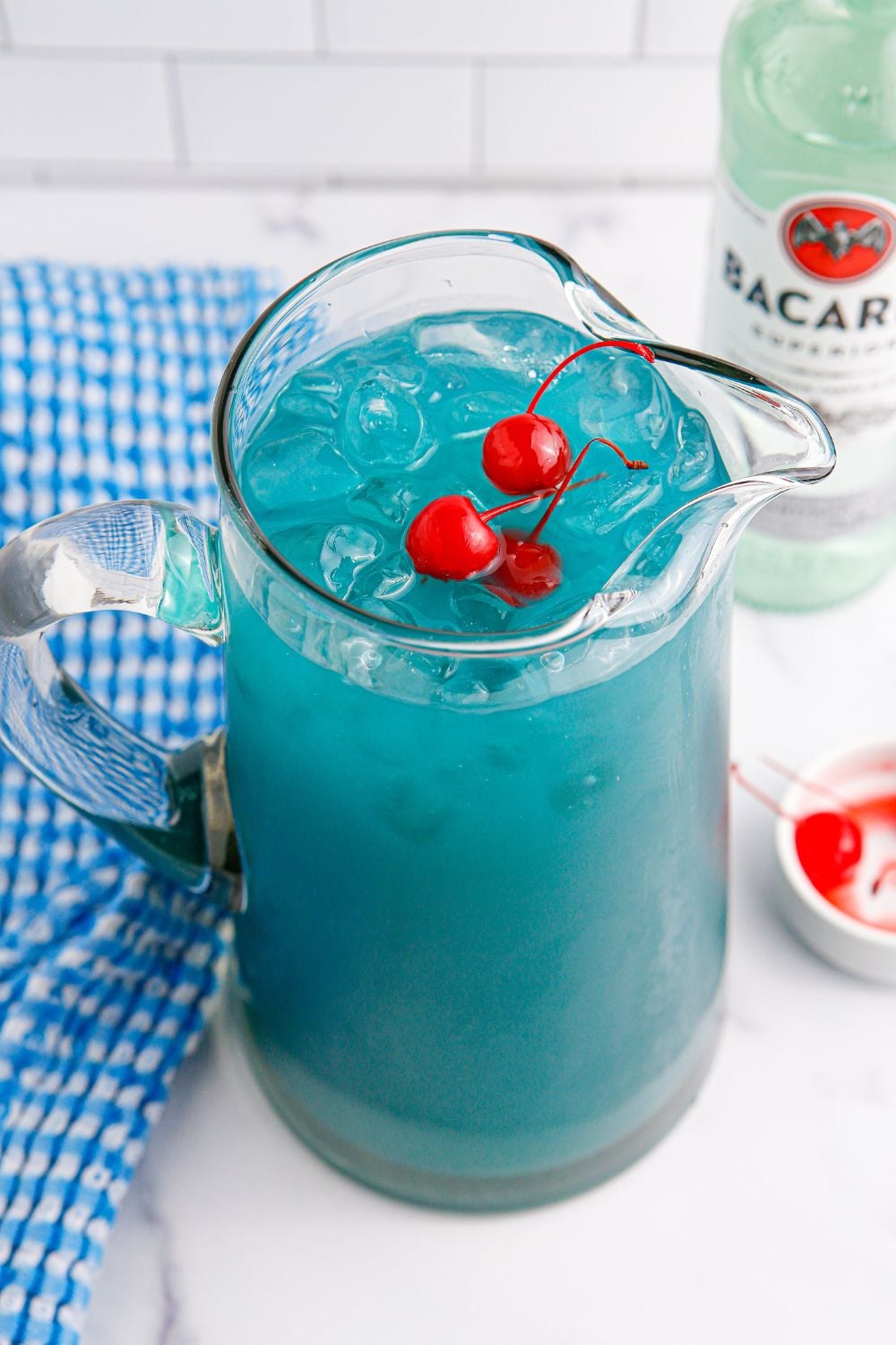 Blue Hawaiian Punch in a pitcher on tabl with a blue checkered towel around it