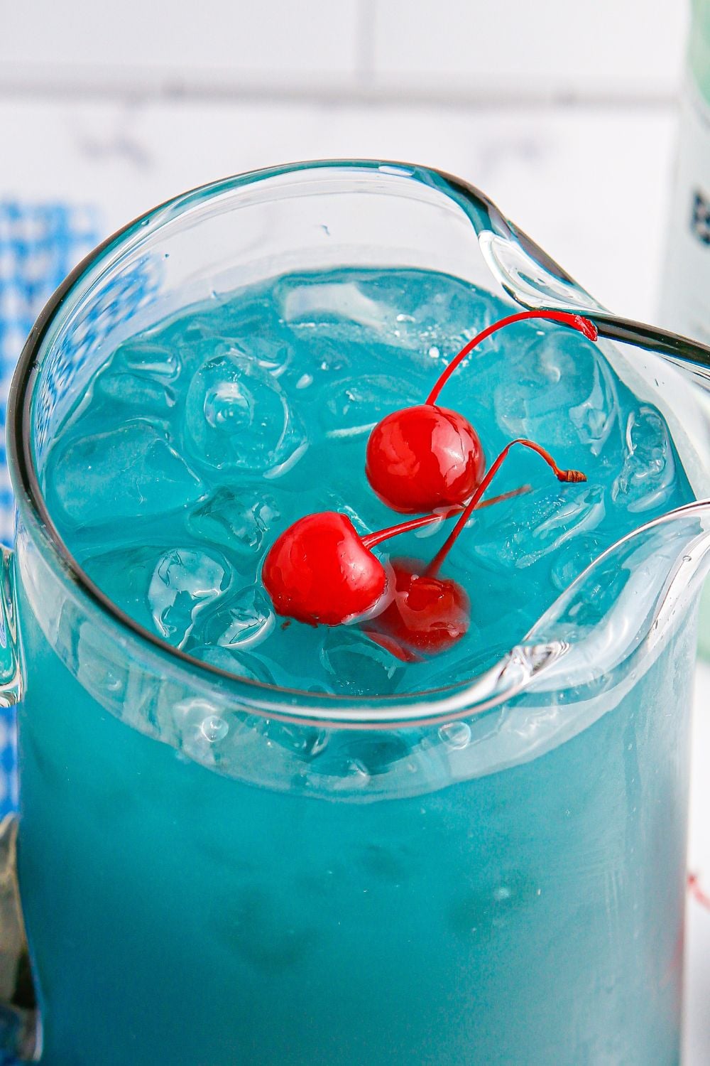 Hawaiian Punch with a few cherries sitting on top of ice in a glass pitcher