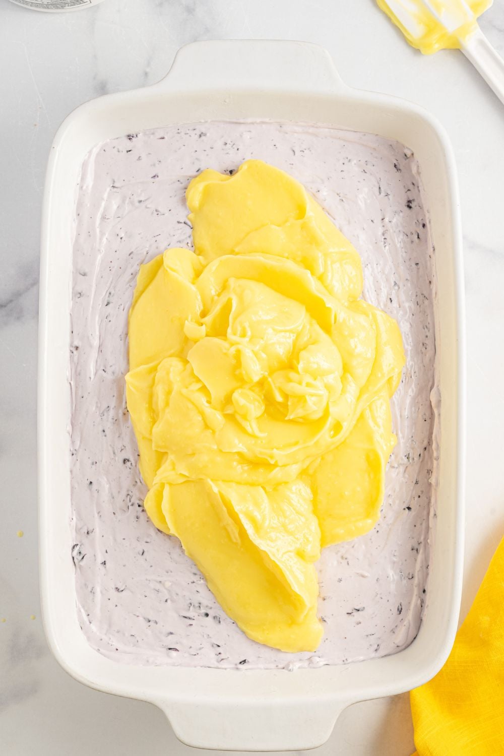 spreading the lemon pudding layer over the top of blueberry cream cheese layer in pan