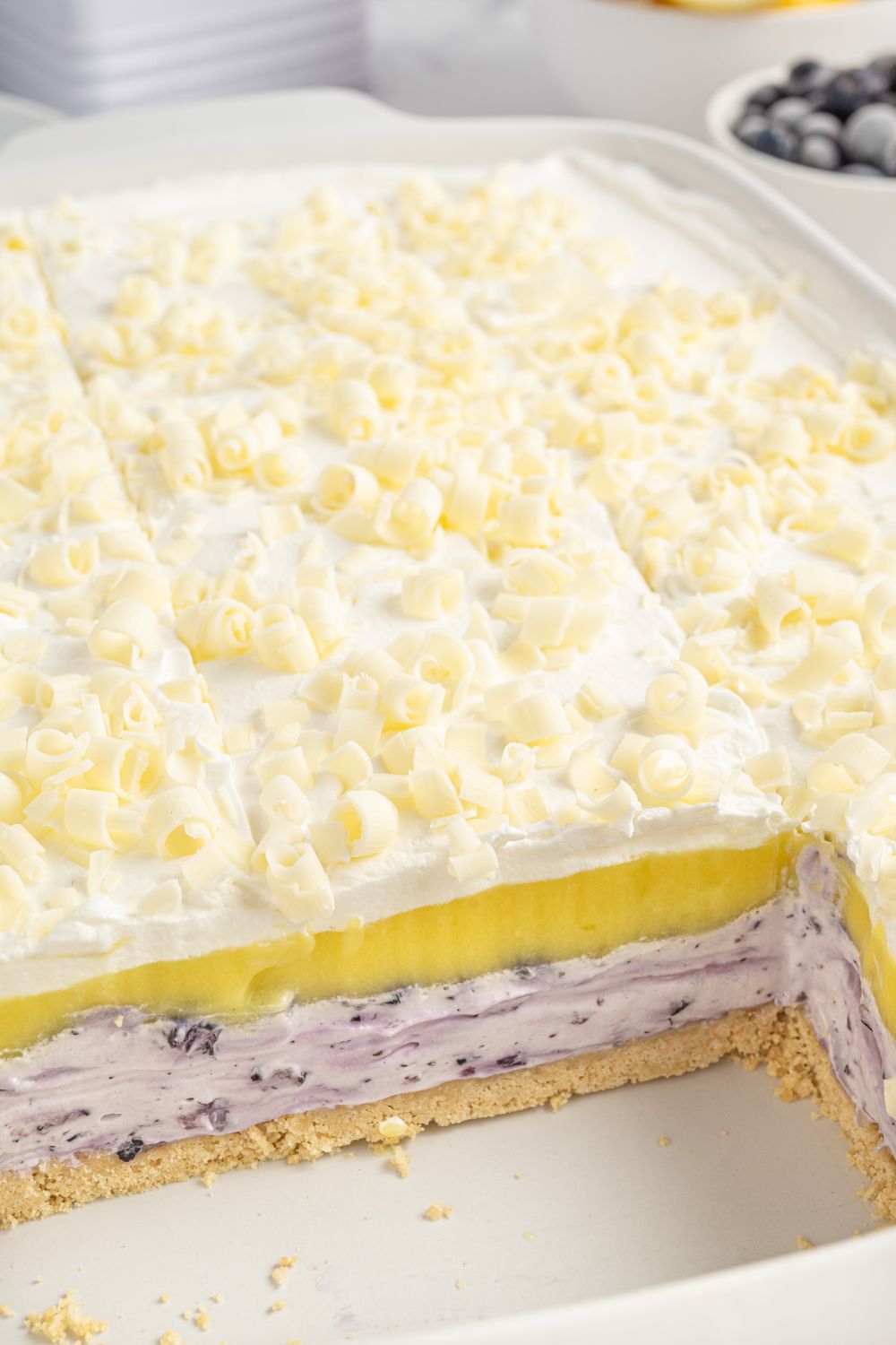 Lemon Blueberry Lush in pan with a few slices removed to see he defined layers in the dessert