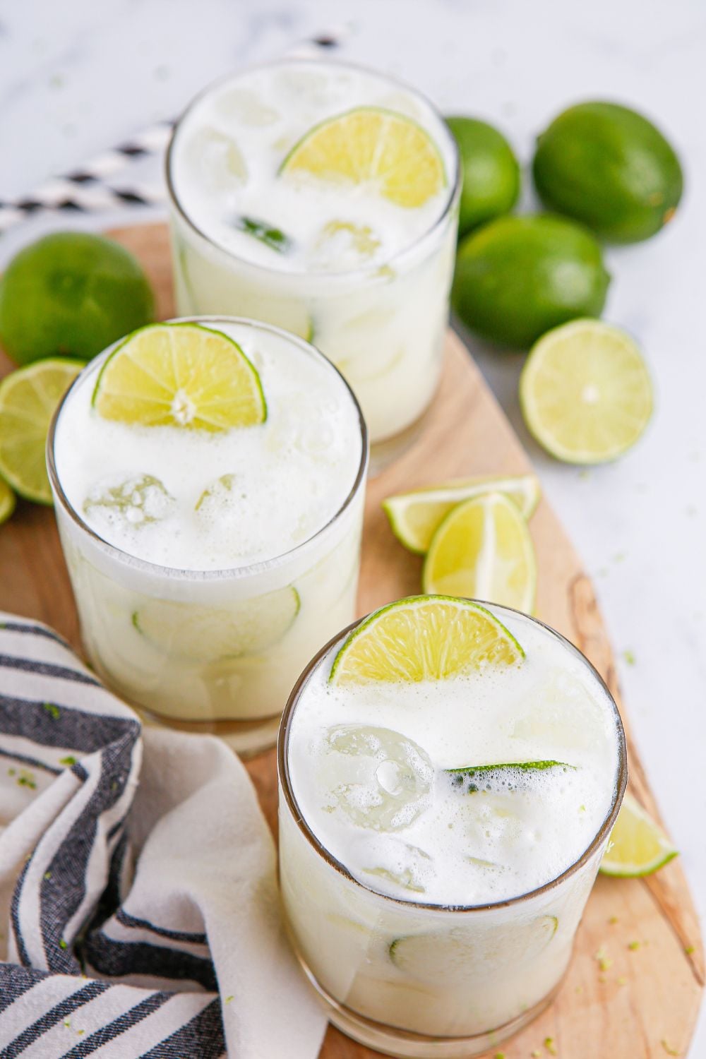 overhead look of brazilian lemonades in glasses with limes scattered on table