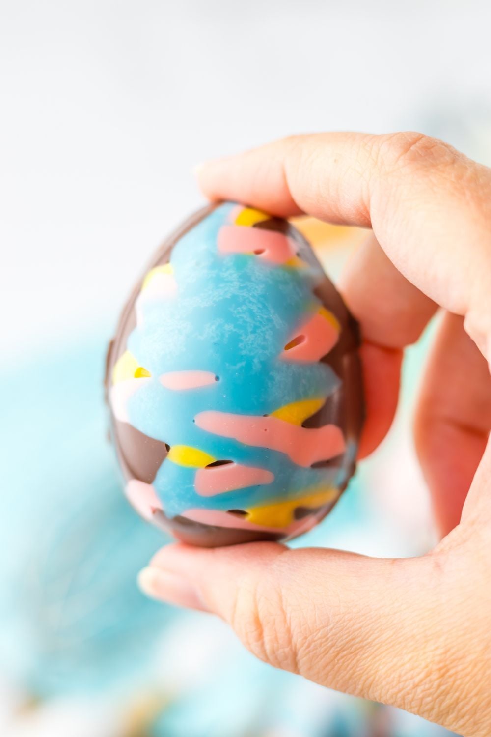 Easter Marshmallow Egg being held in a hand above the table 