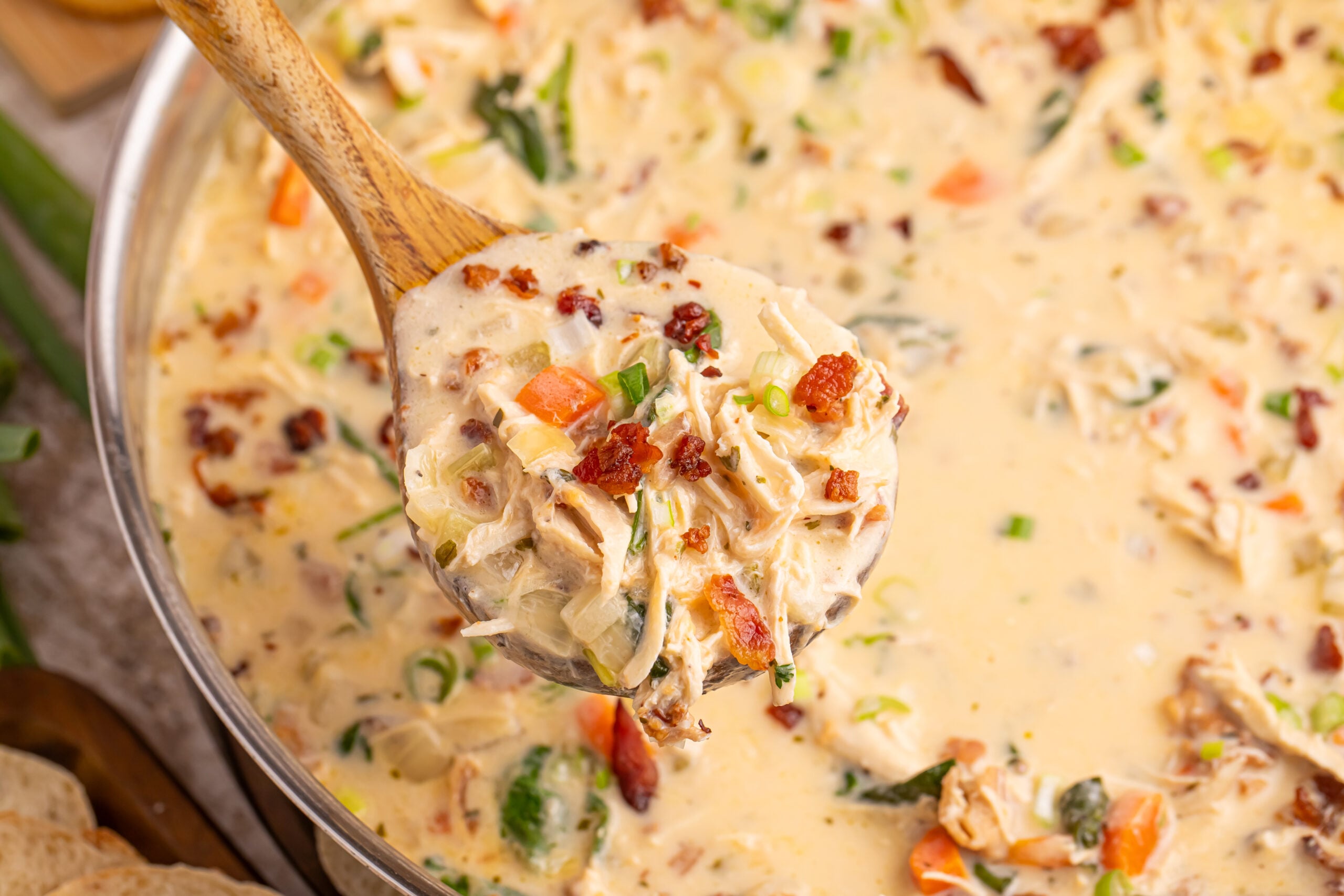Crack Chicken Soup in a pan with a wooden spoon full of soup being held above the pan