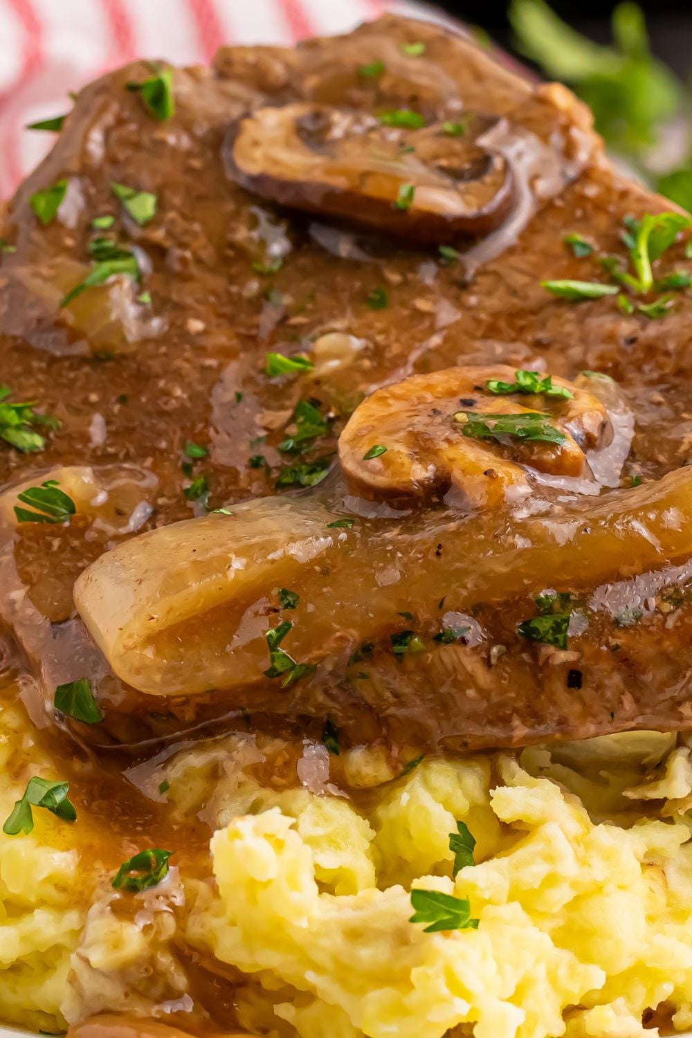 Round Steak and Gravy on a plate with a close up to se the mushrooms and onions in the thick brown gravy on top of steak