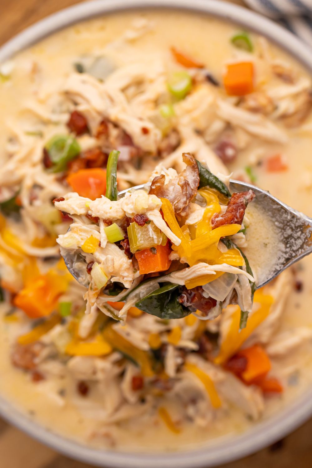 Crack Chicken Soup in a white bowl on table with a spoon of soup being held above the pan