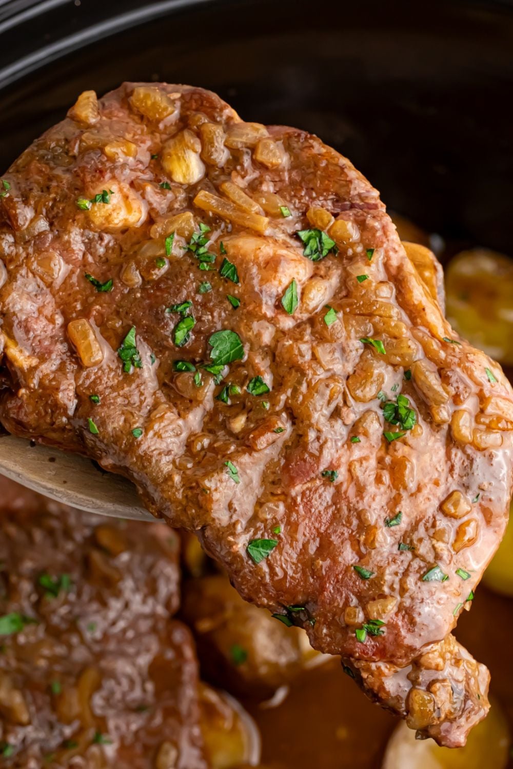 steak on spoon lifted out of crock pot, showing Crock Pot Steak and Potatoes
