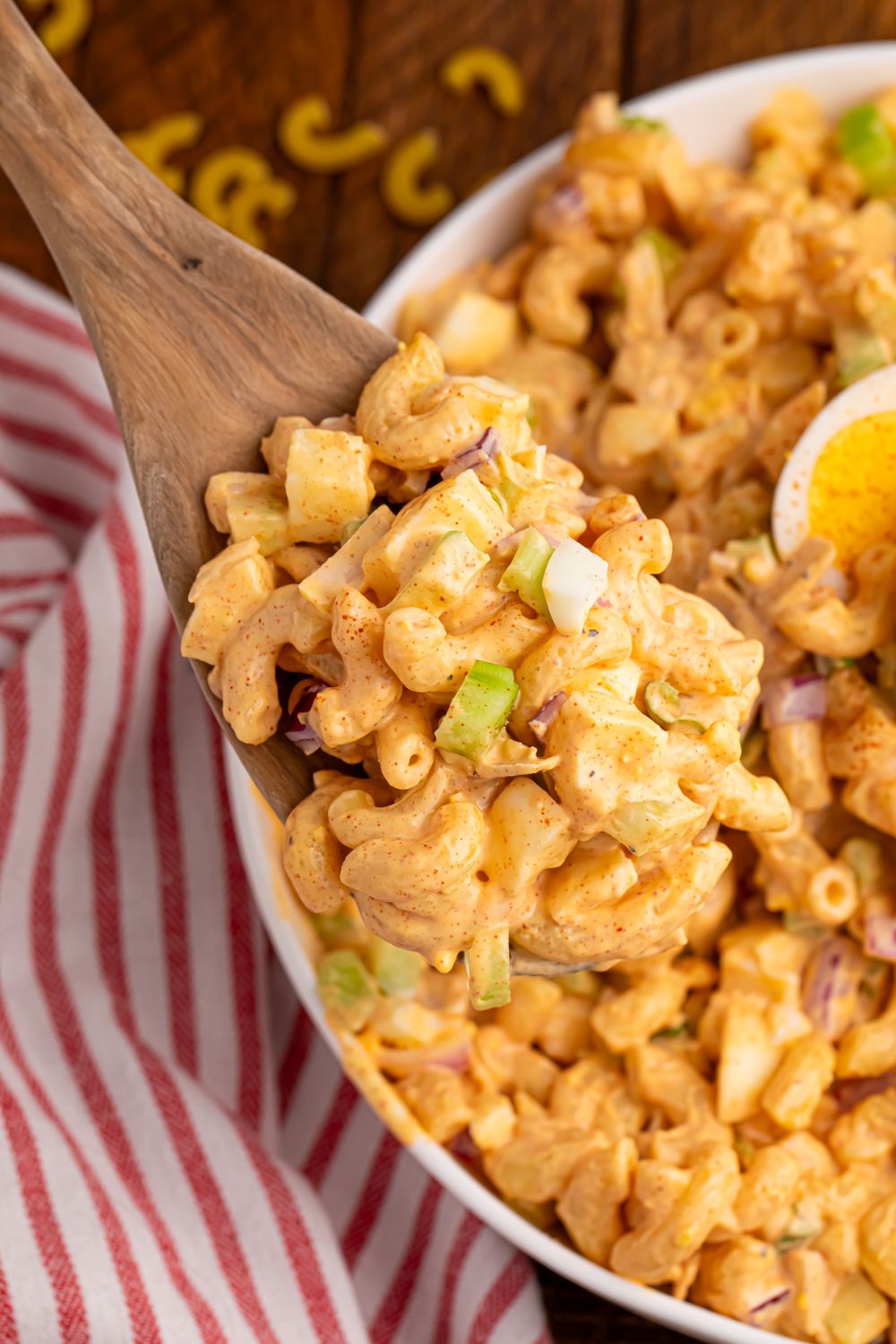Deviled Egg Pasta Salad in a bowl with a wooden spoon full of the salad