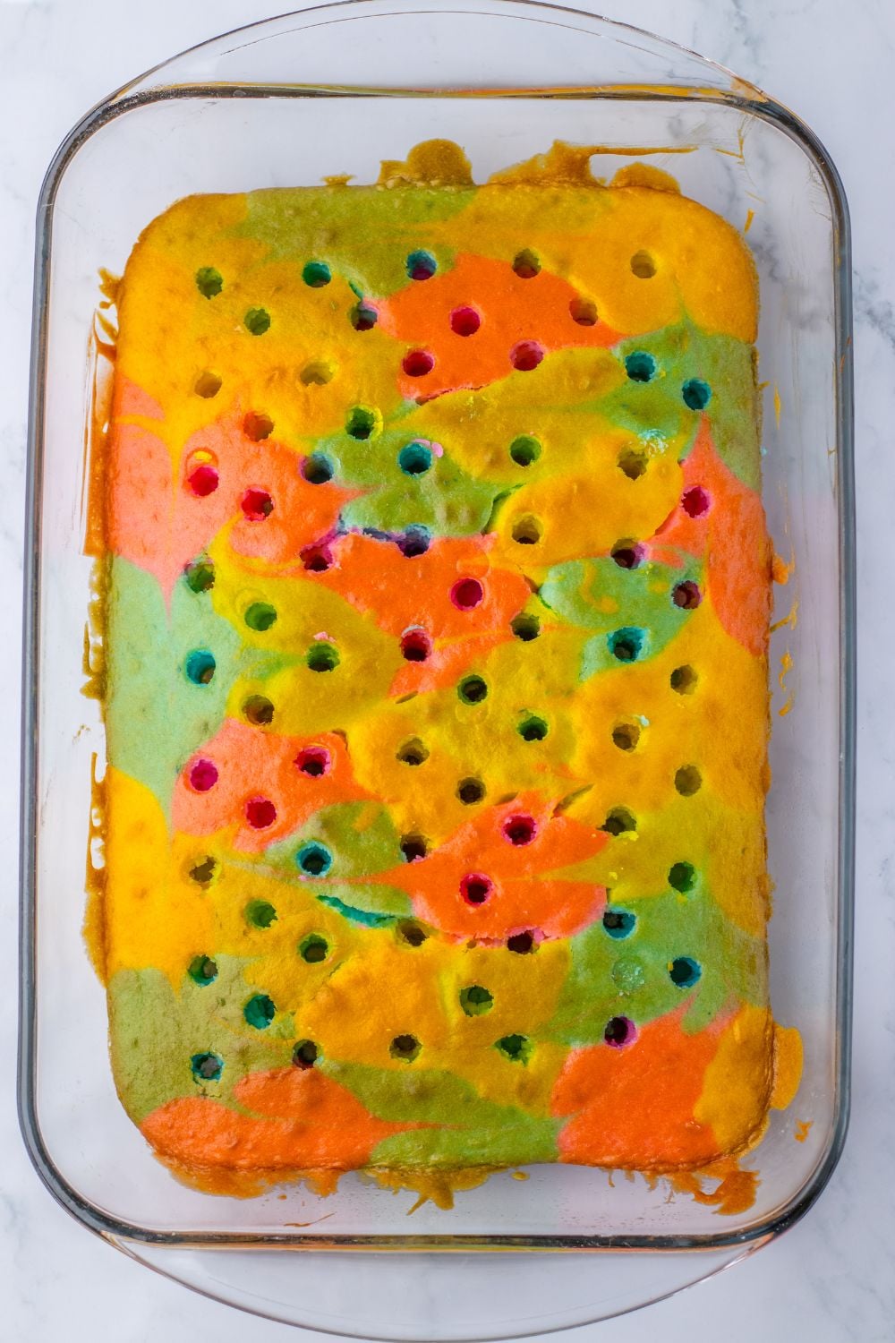 Easter Poke Cake on table in pan with holes poked all over the cake