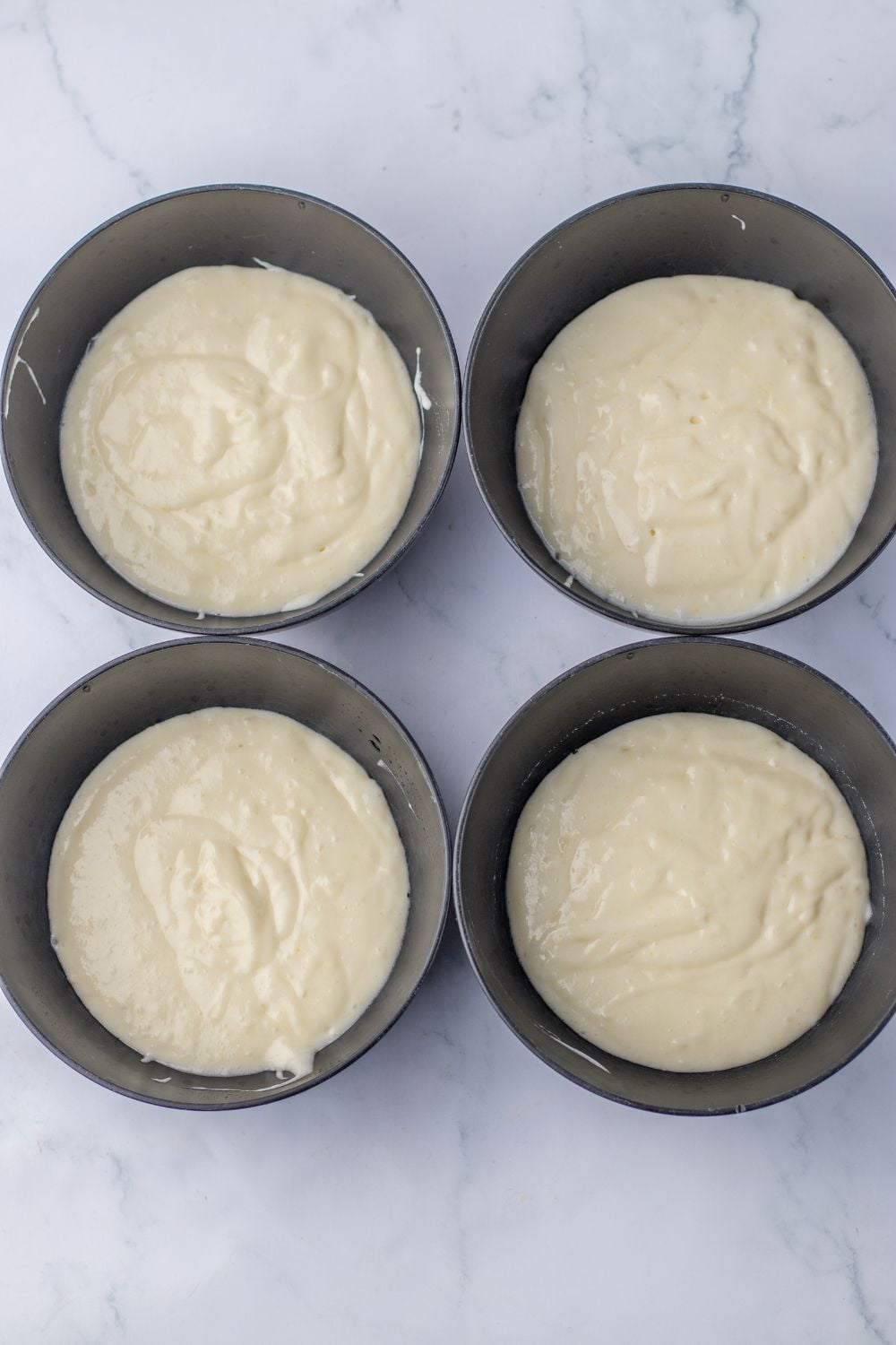 white cake mix mixed up and poured into 4 bowls sitting on tabl for making the Easter Poke Cake
