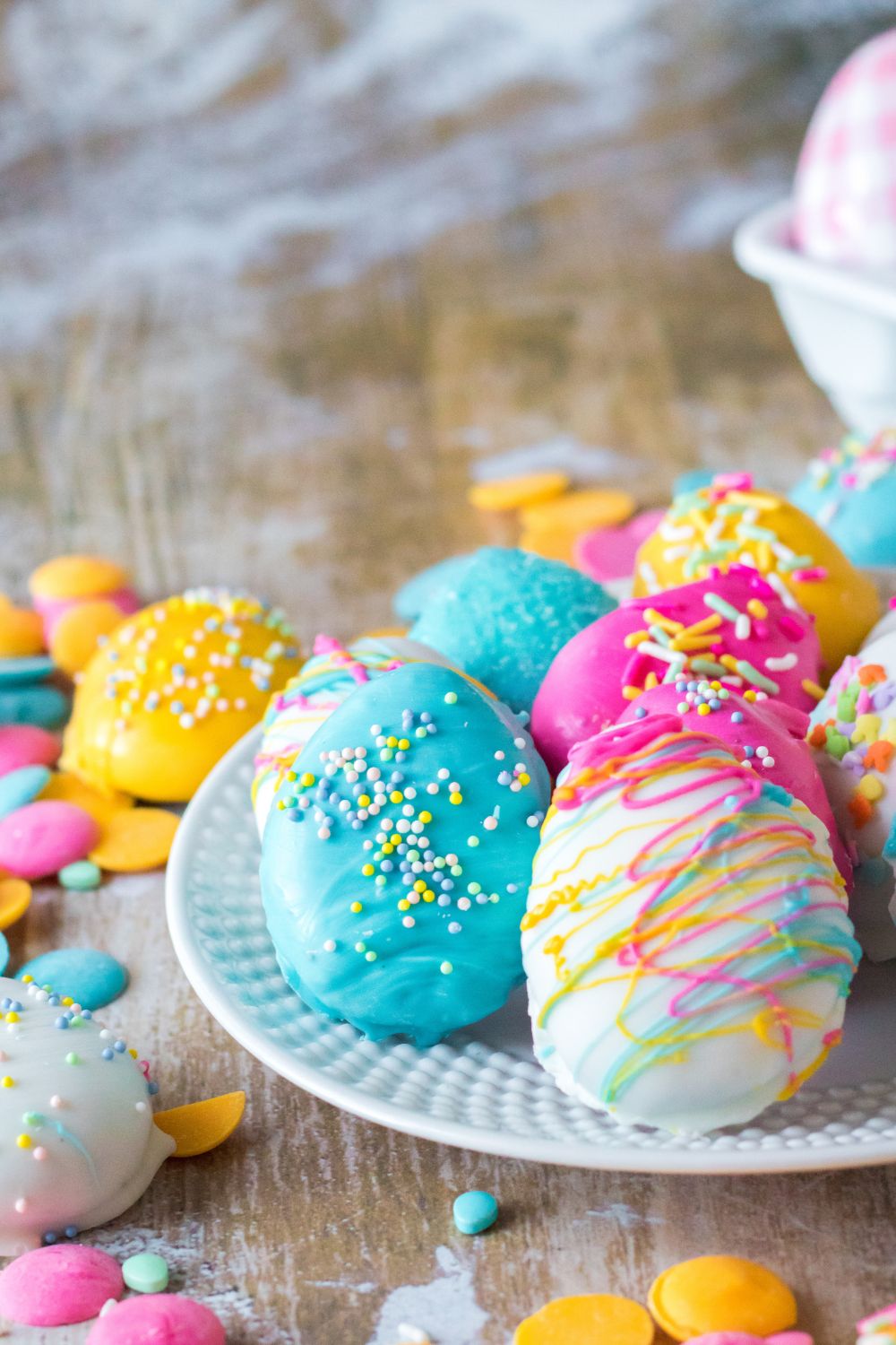 Easter Egg Oreo Truffles on table and on a white plate with sprinkles around it and Easter decor