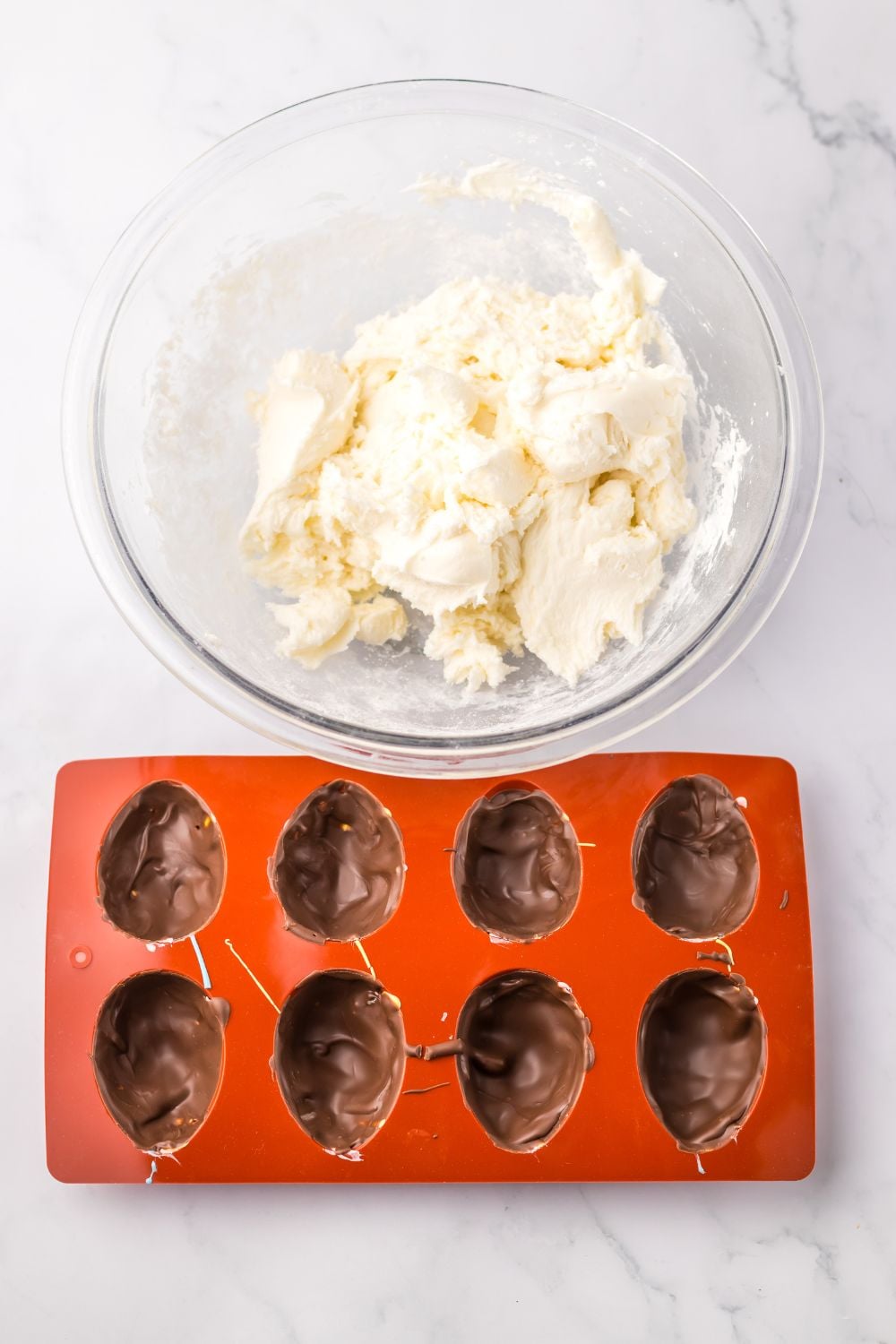 chocolate coating in a silicone mold ith marshmallow mixture in bowl by it for making a Easter Marshmallow Eggs