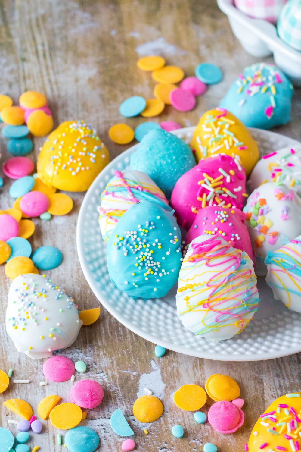 Easter Egg Oreo Truffles on tabl and on a white plate with candy melts and sprinkles decorated around it