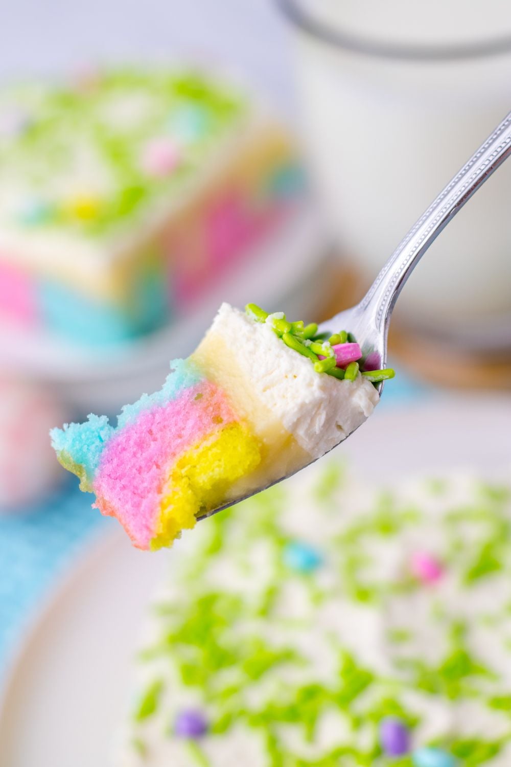 slice of Easter poke cake on plate with a fork with a bite on it