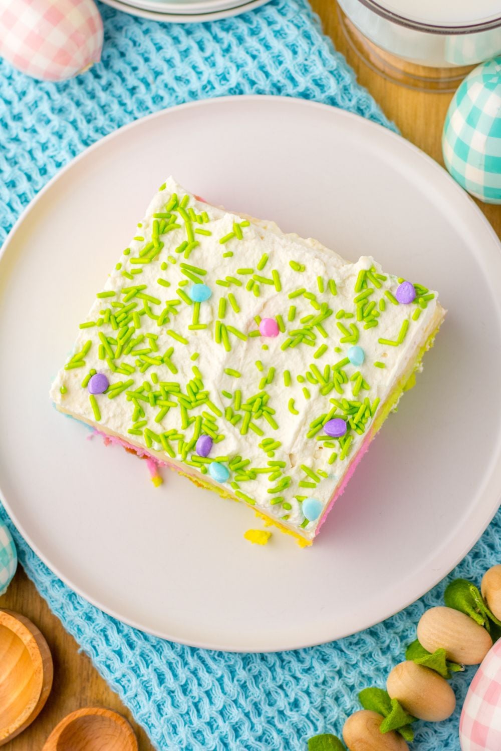 overhead look of a slice of Easter Poke Cake on a plate topped with green and pastel sprinkles