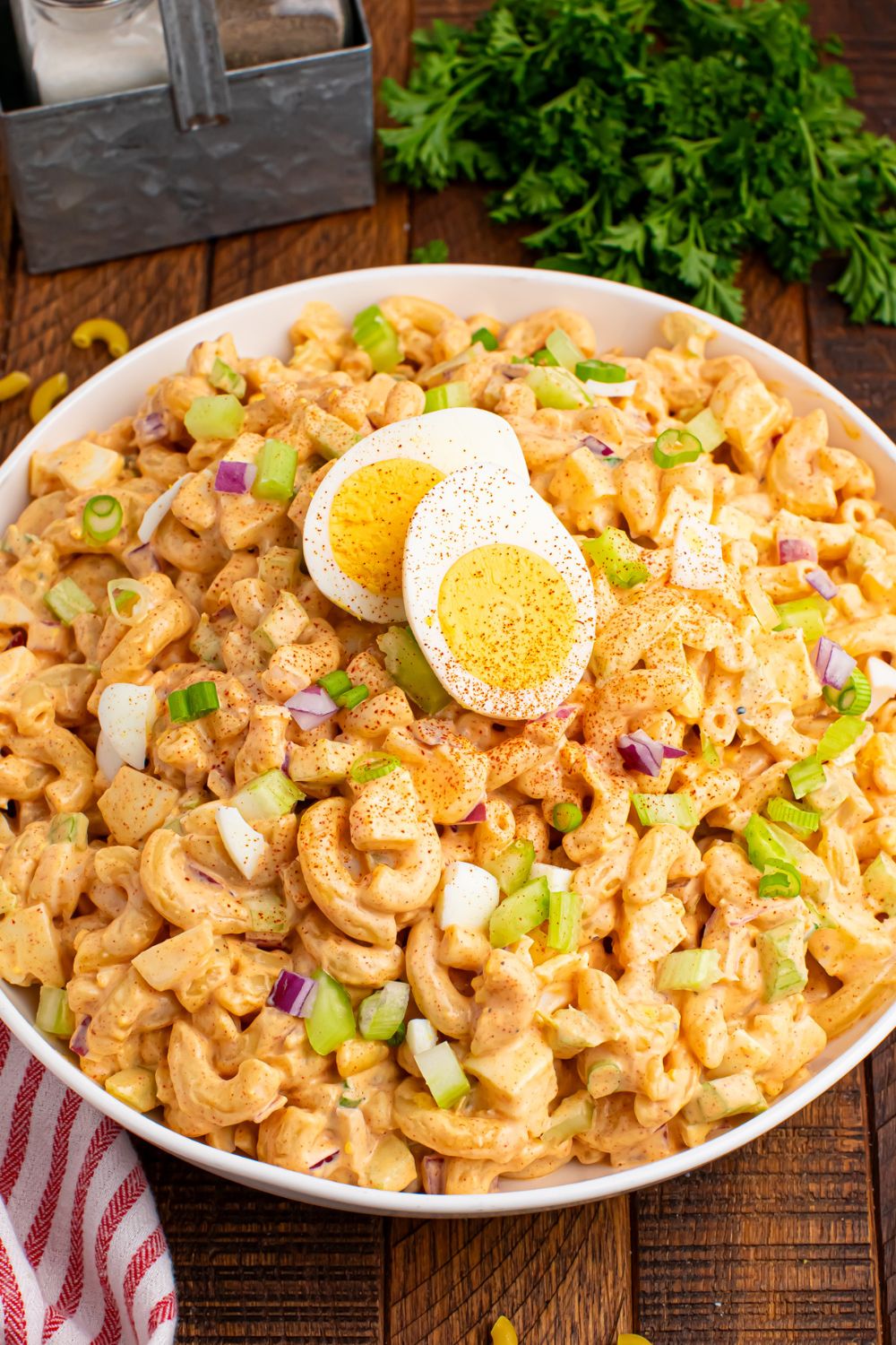 Deviled Egg Pasta Salad in a bowl on table with a hard boiled egg slicd in half and placed on top