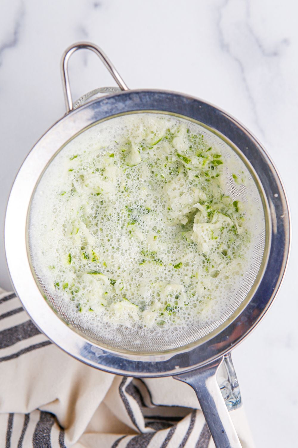 creamy limemade mixture being strained from a strainer