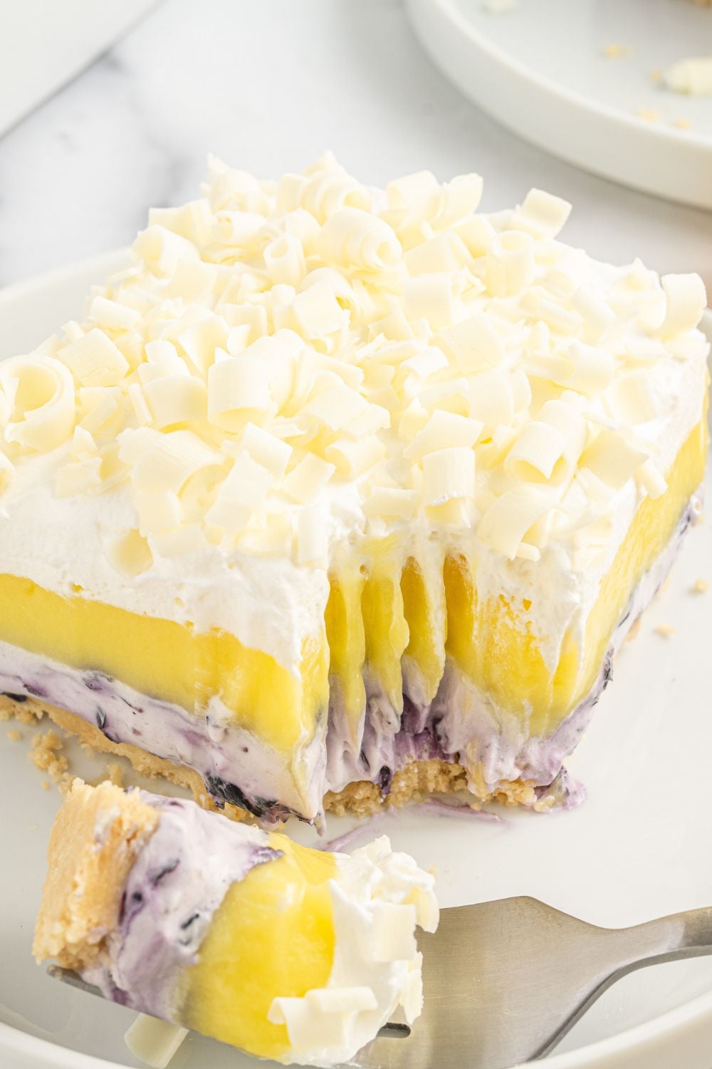Lemon Blueberry Lush dessert sitting on plate with a fork bite taken out of it