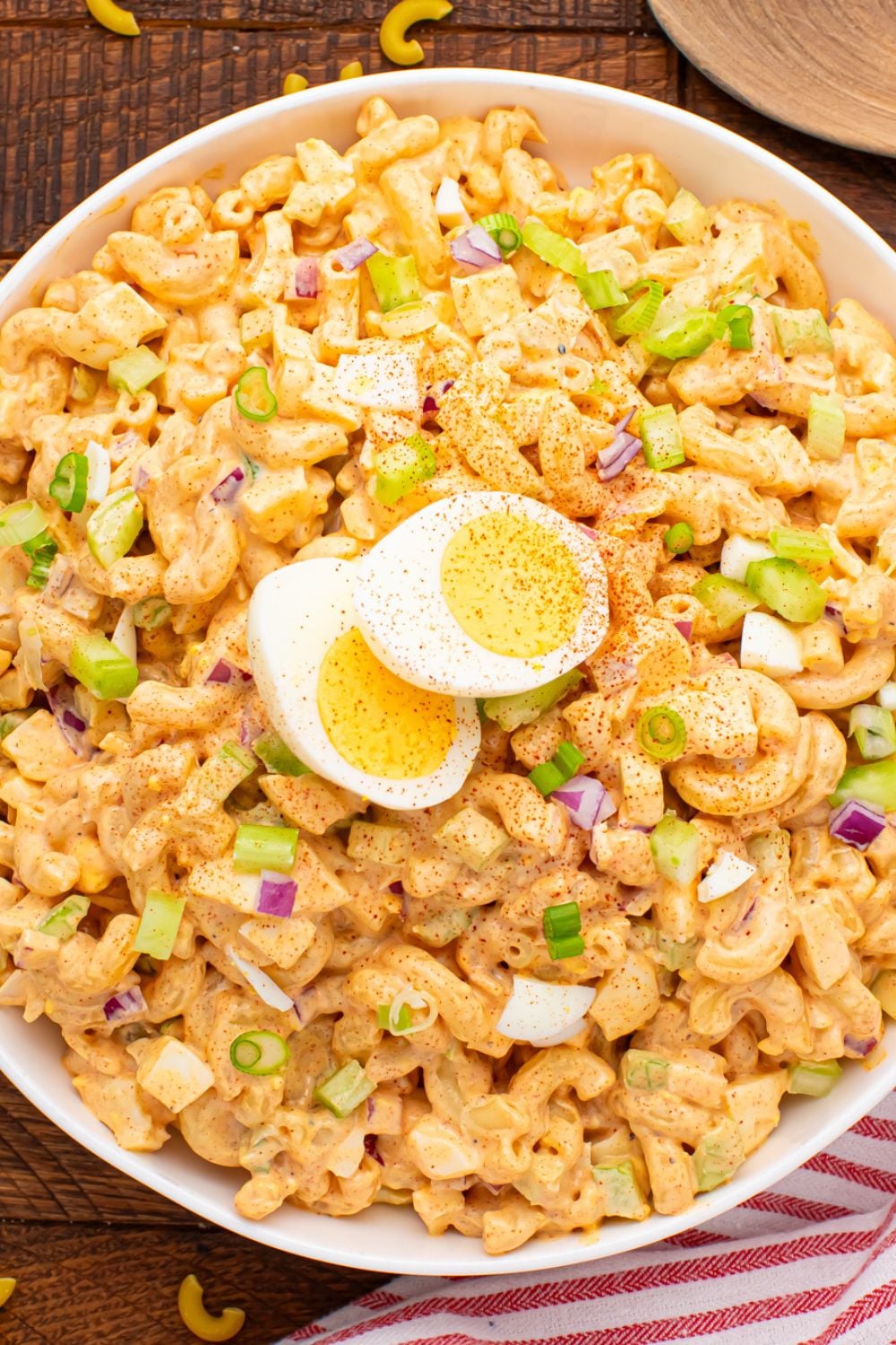 overhead look of pasta egg salad in a white bowl with dried pasta around the bowl