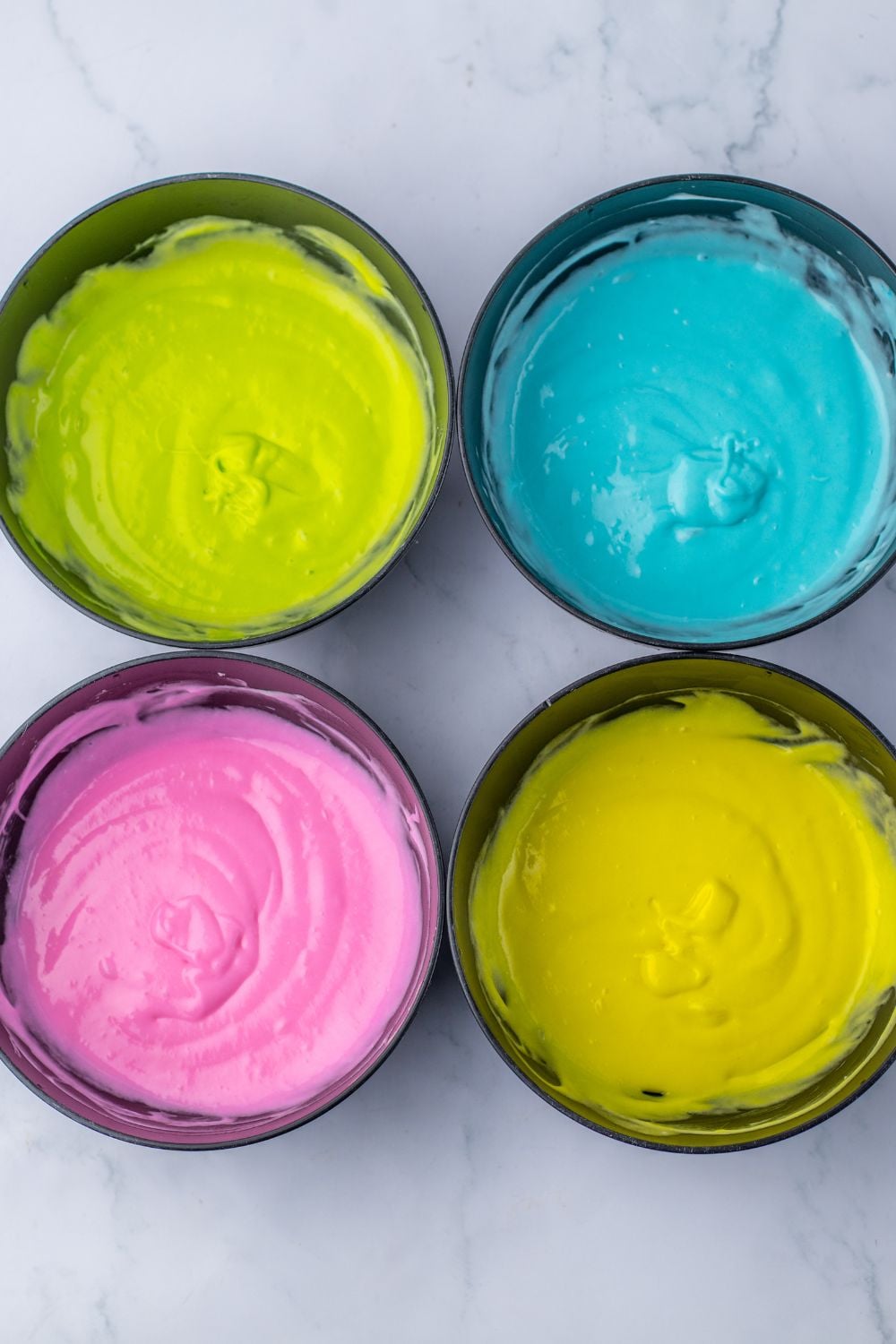 4 bowls of colored cake mix for making the Easter Poke Cake