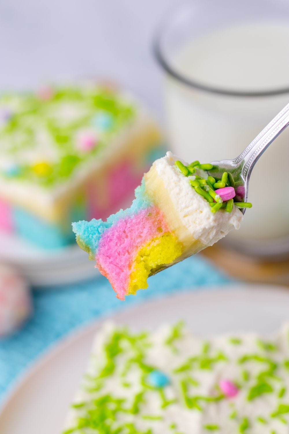Easter Poke Cake sliced on plates with a fork with a bite of th cake showing the pastel colors of the cake