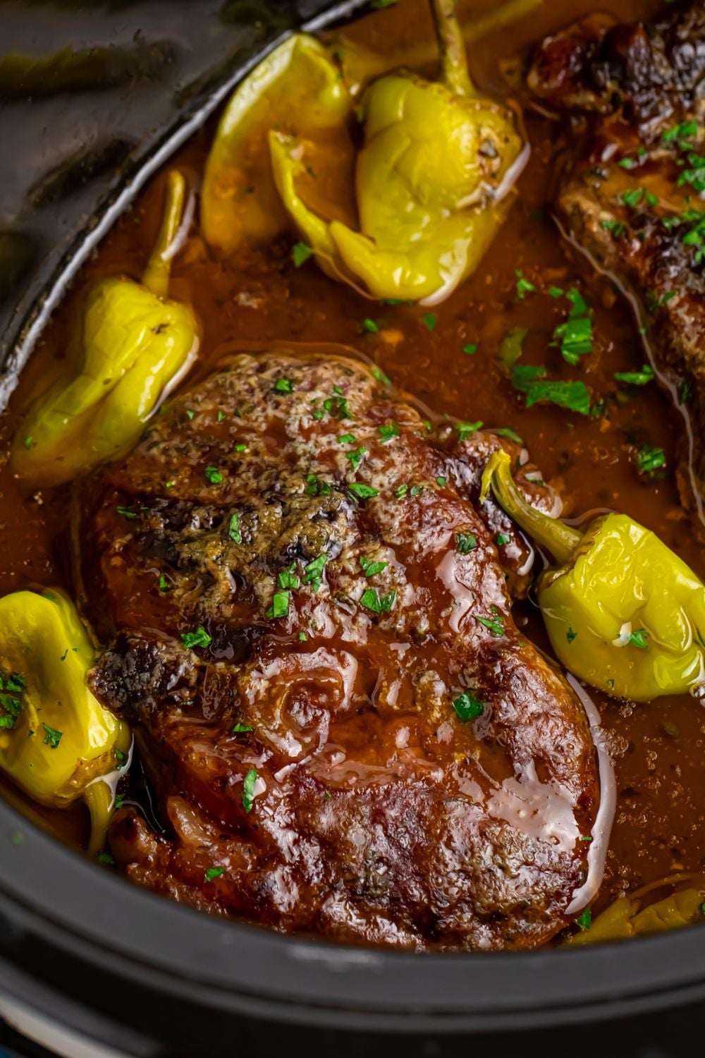 Slow Cooker Mississippi Ribeye Steaks in pot with a close up with peppers around it