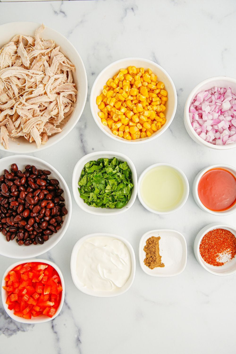 Southwest Chicken Salad ingredients in bowls sitting on a marble counter