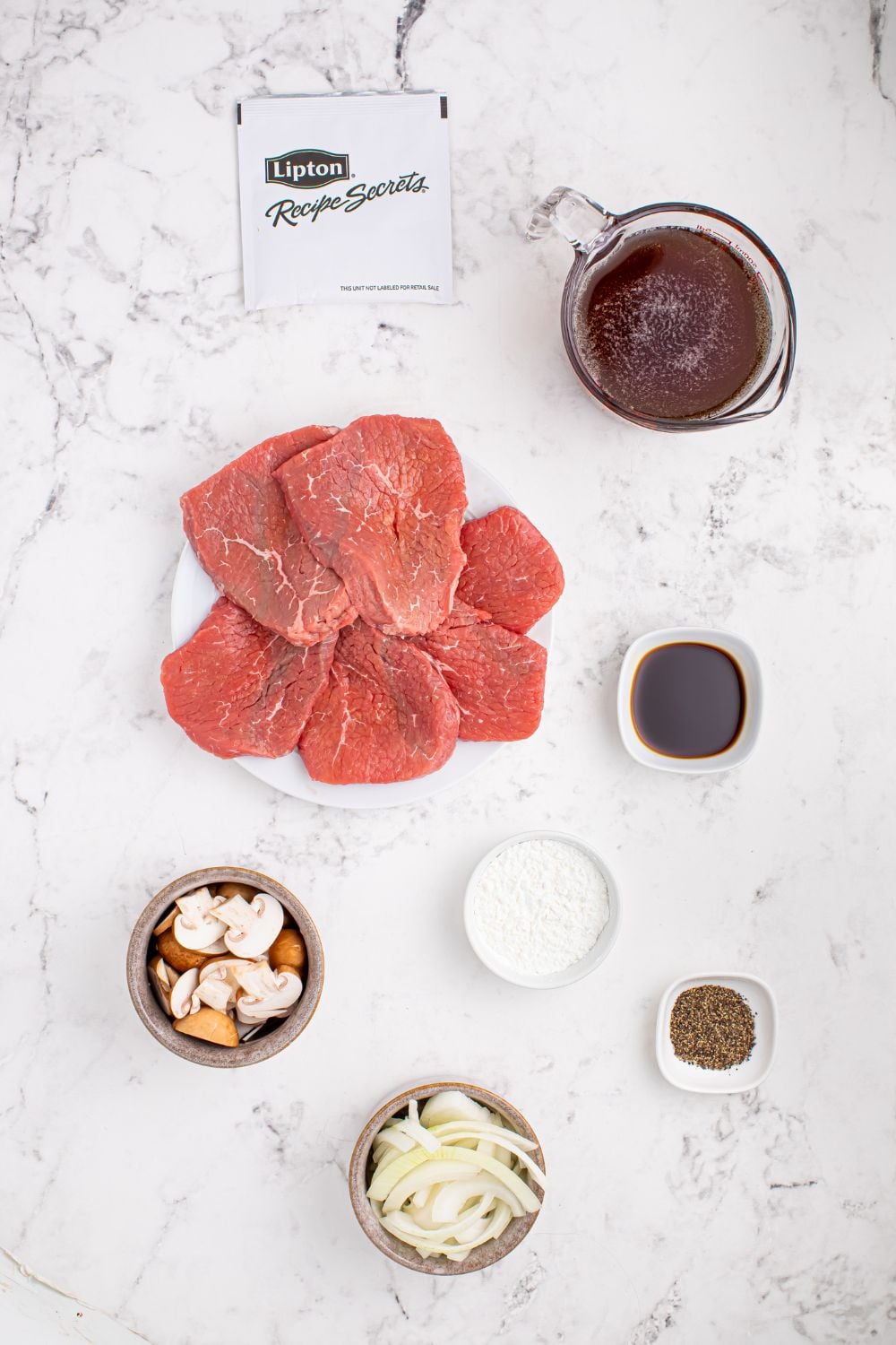 Slow Cooker Round Steak and Gravy ingredients in single serve containers on a marble countertop