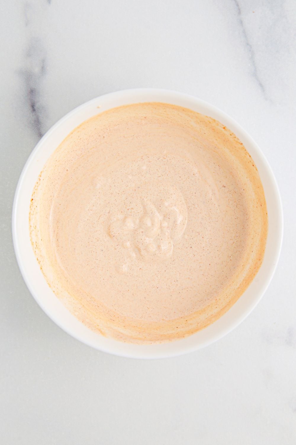 creamy sour cream dressing in a white bowl on table
