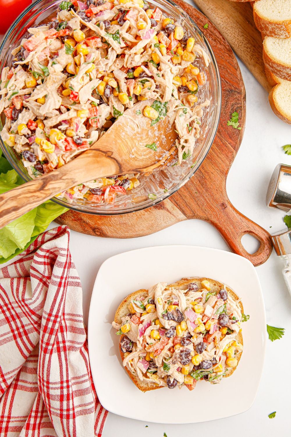 Southwest Chicken Salad on a plate with a slice of bread topped with salad, and a bowl of salad sitting behind it