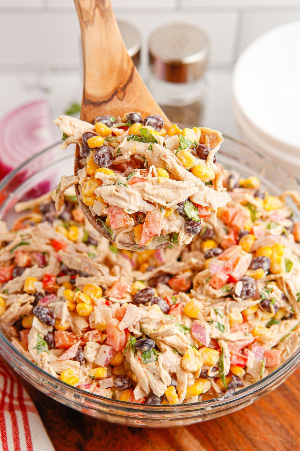 Southwest Chicken Salad in a bowl with a wooden spoon lifting some of the salad out of the bowl
