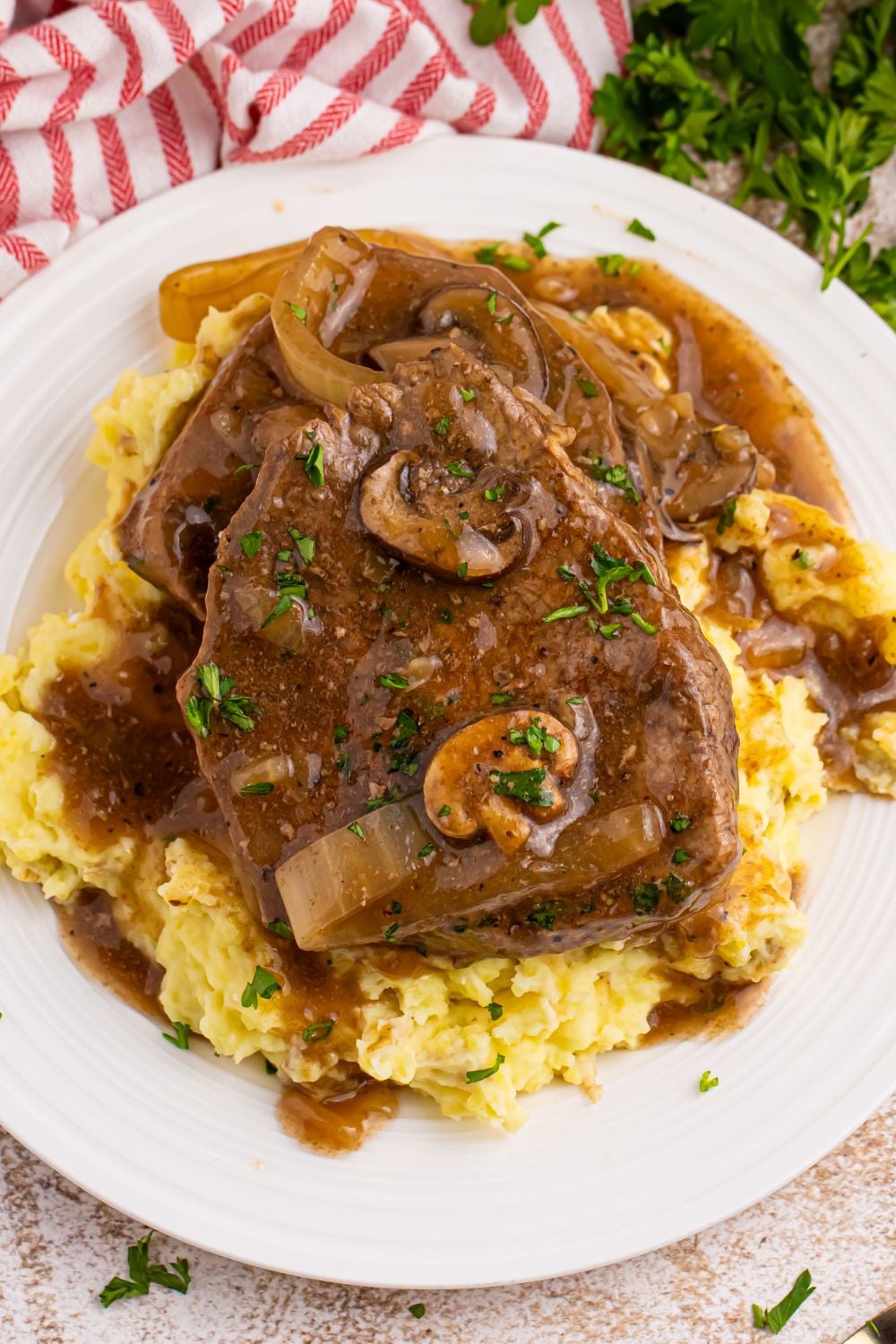 steak on top of mashed potatoes smothered in gravy from the Slow Cooker Round Steak and Gravy recipe