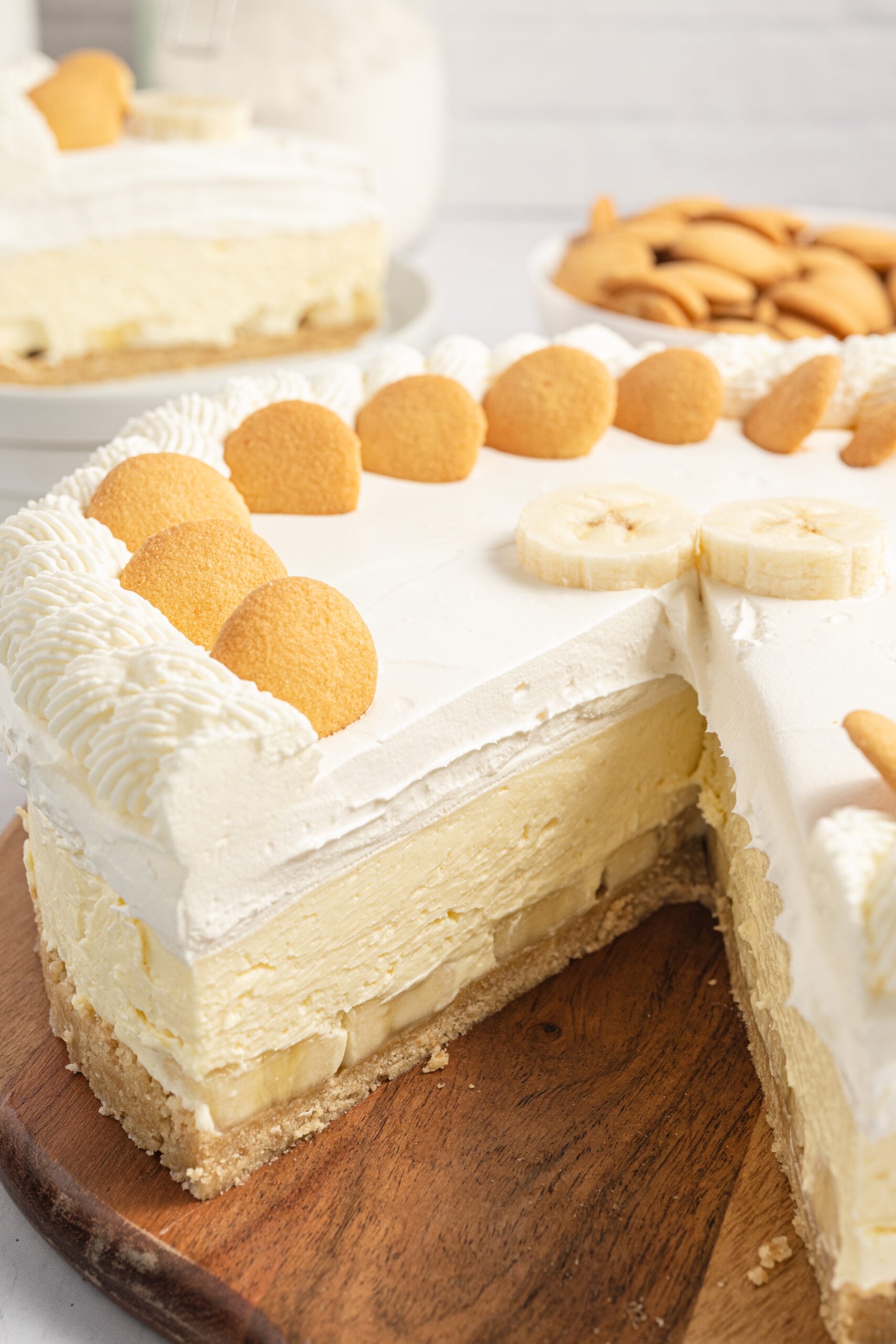 view of a banana pudding cheesecake sliced and on a wooden cutting board on table