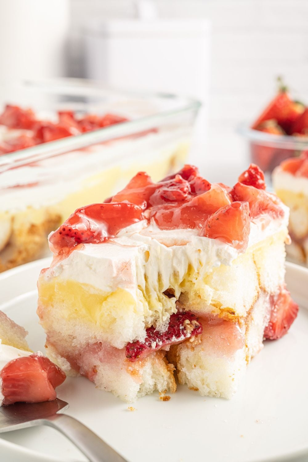 slice of heaven on earth strawberry cake on a plate with a fork with a bite on it