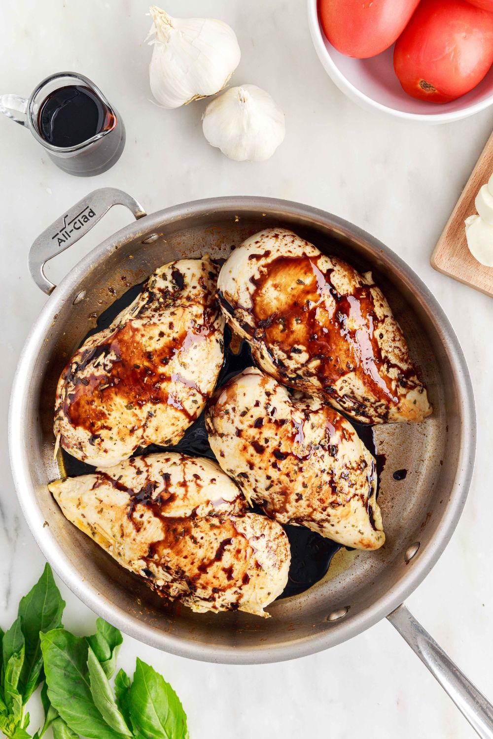 balsamic glaze poured on top of Caprese Stuffed Chicken in a pan 
