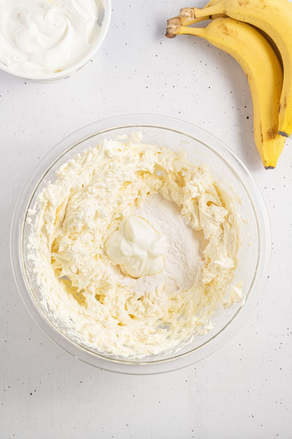 cream cheese mixed up in a bowl with pudding mixture in the center for making a banana pudding cheesecake