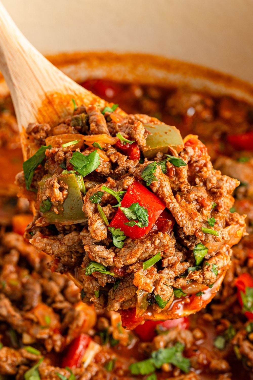 wooden spoon over Dutch Oven with beef picada on the spoon
