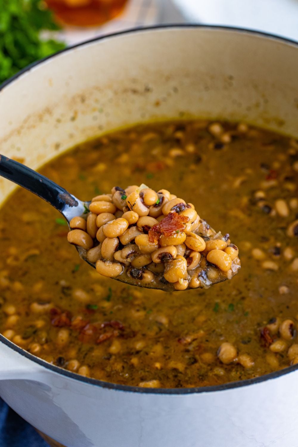 Dutch oven with a spoonful of black eyed peas and a pot of black eyed peas