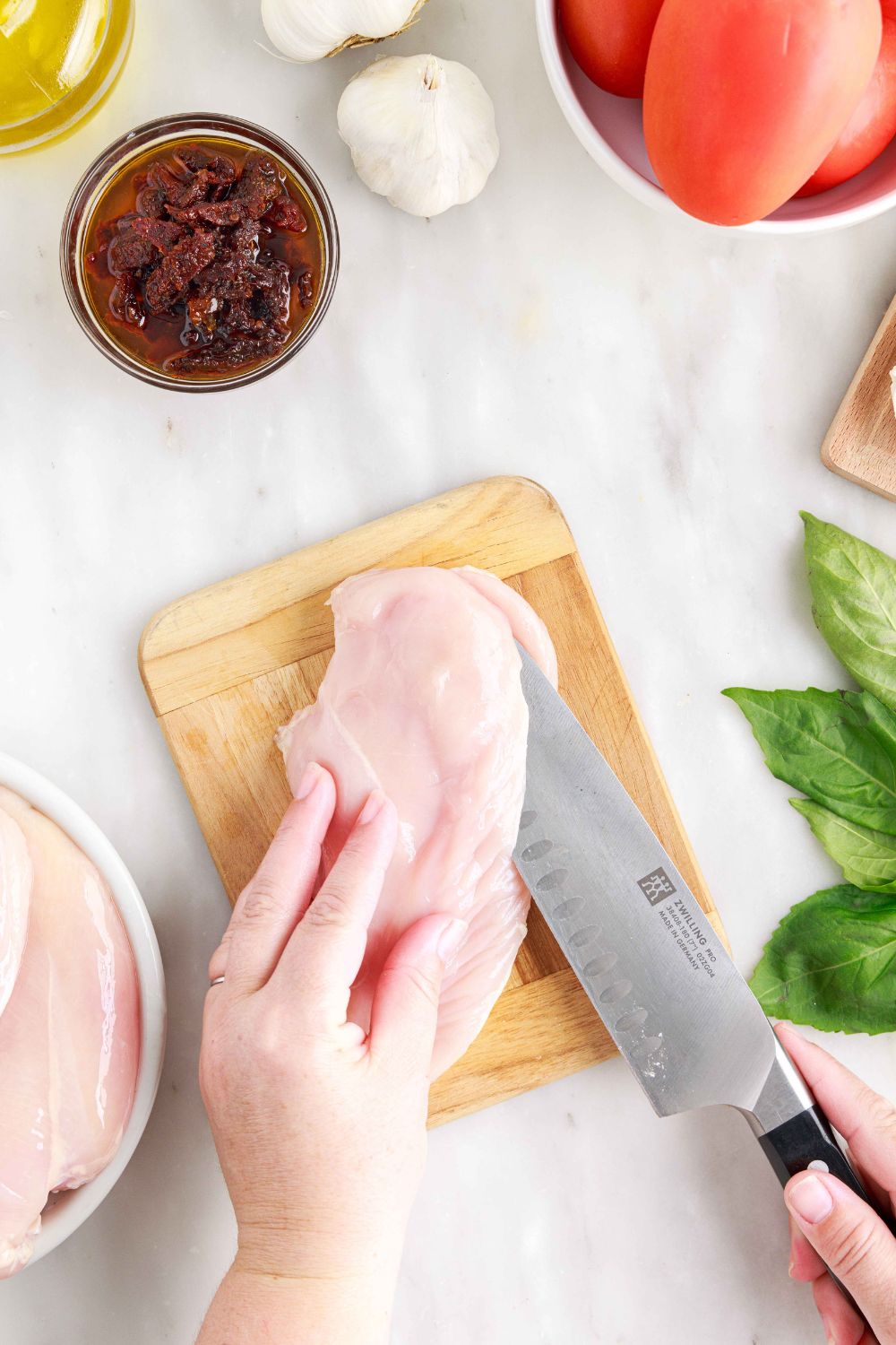 raw chicken on cutting board being butterfly cut 