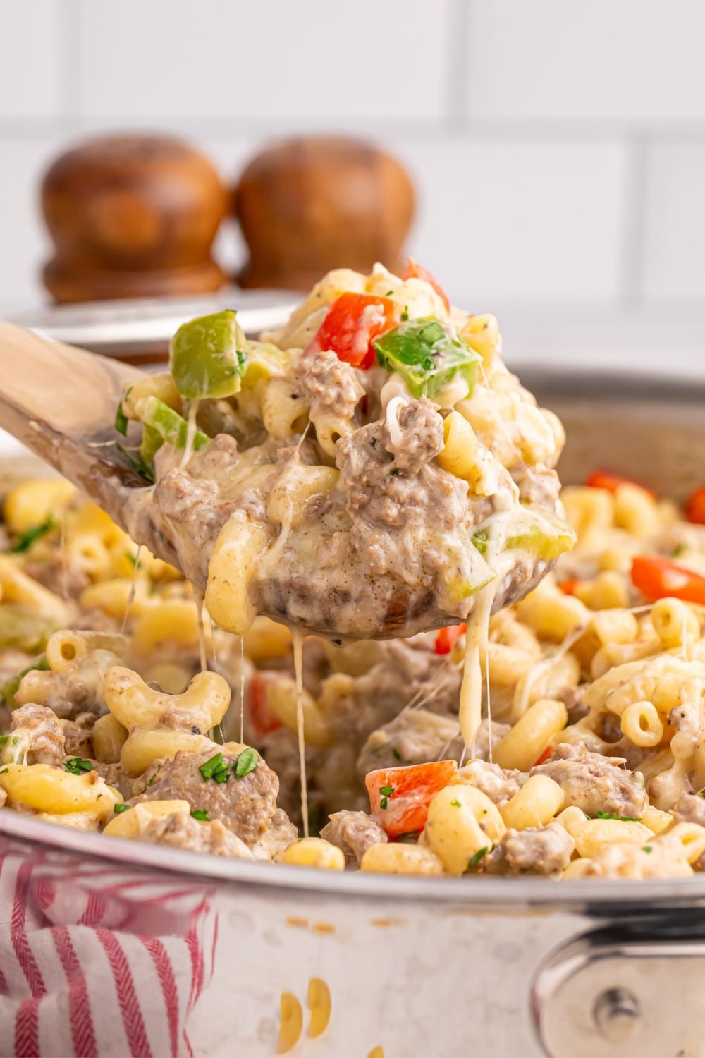 Philly Cheesesteak Pasta in skillet with a spatula scooping some pasta up with some strings of cheese