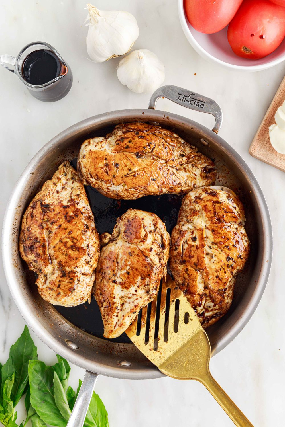 Caprese Stuffed Chicken in pan being flipped with a spatula 