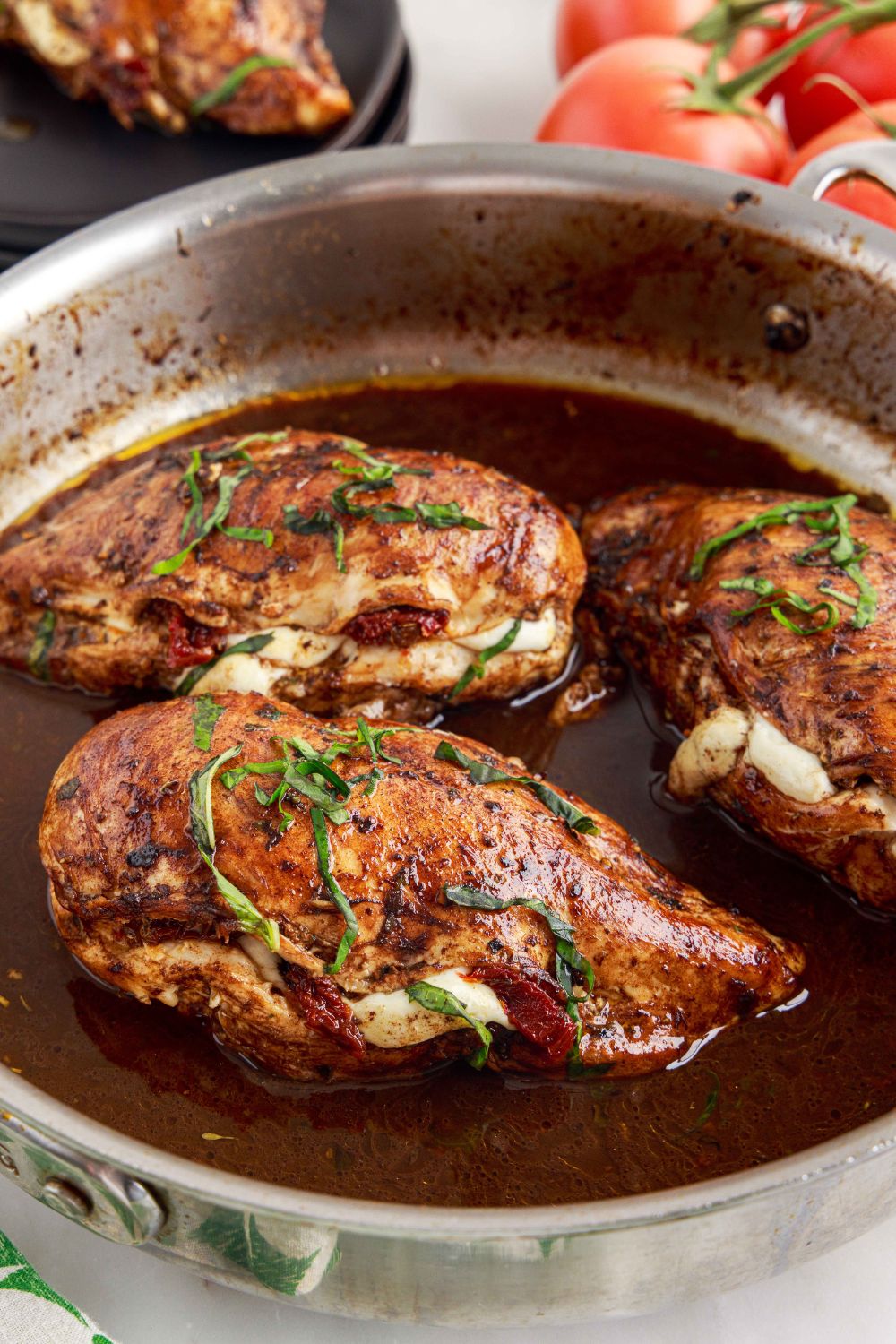 Caprese Stuffed Chicken in a skillet with sauce in the pan as well 