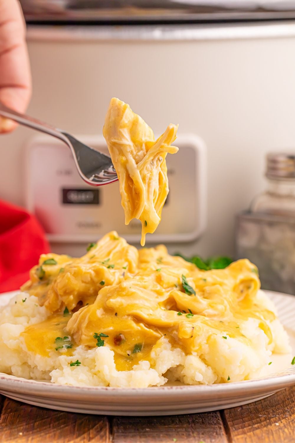 plate with chicken, gravy, and mashed potatoes on it. A fork with meat is being lifted above the plate 