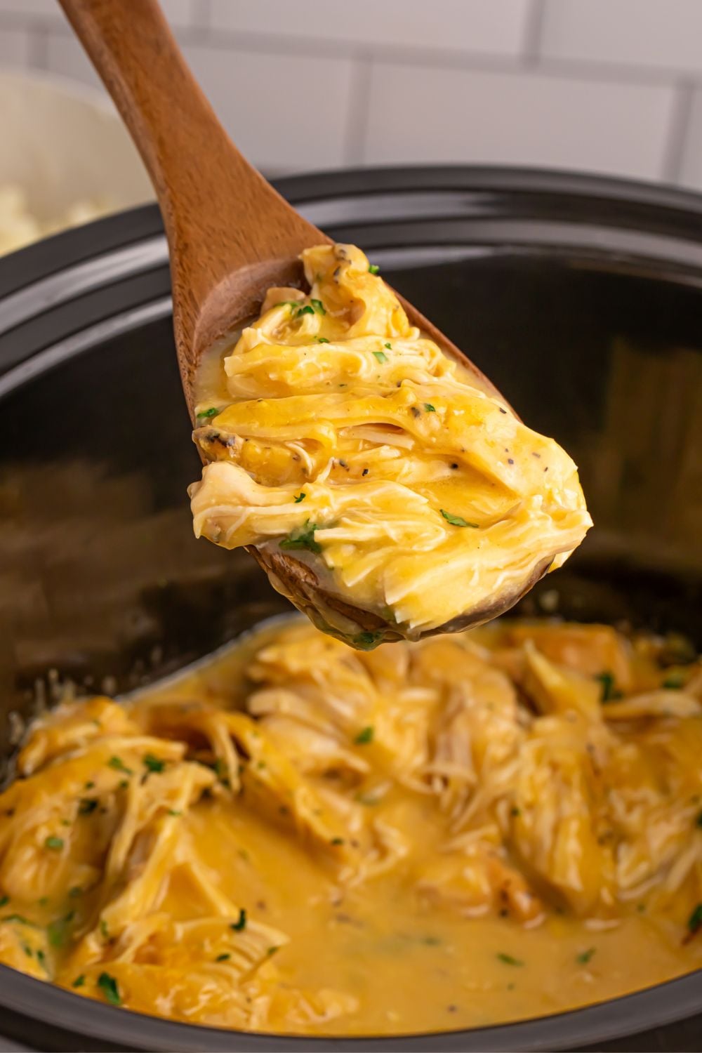 Chicken and Gravy in a crockpot with a wooden spoon full of chicken and gravy 